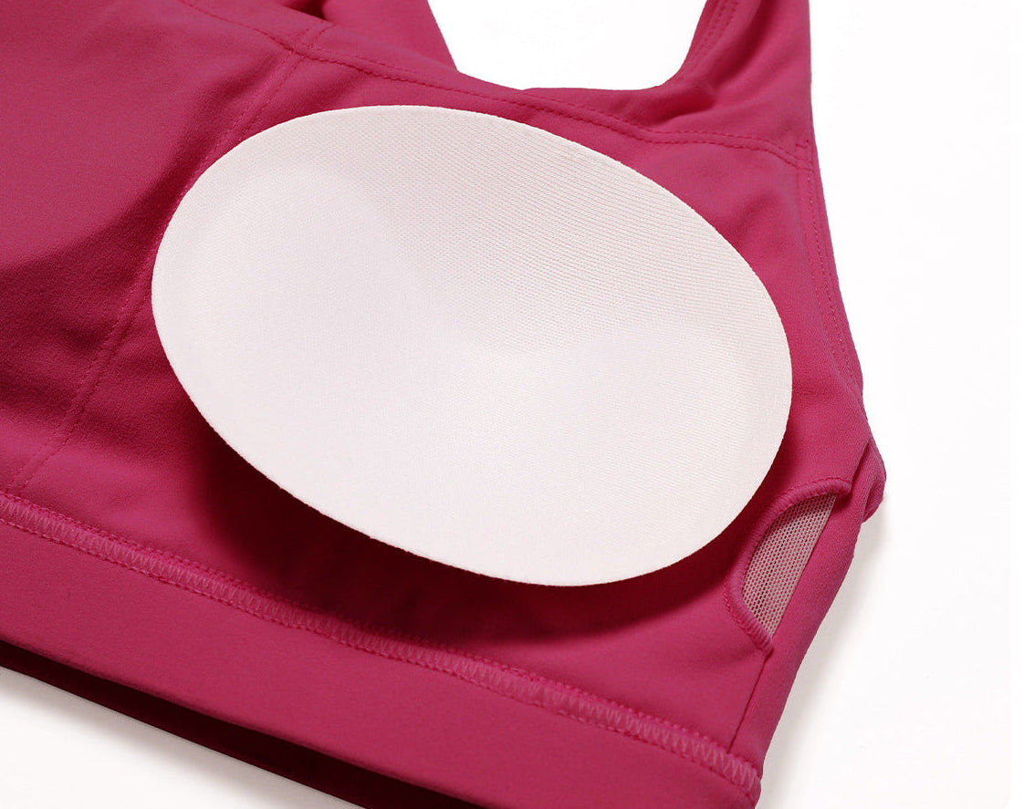 A close-up of a magenta sports bra with a white oval underwire insert cup, shown against a plain white background.